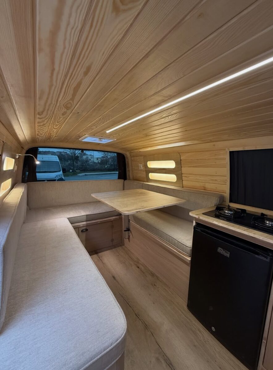 Sitzgruppe mit Tisch und Küchenzeile im Camper-Ausbau
